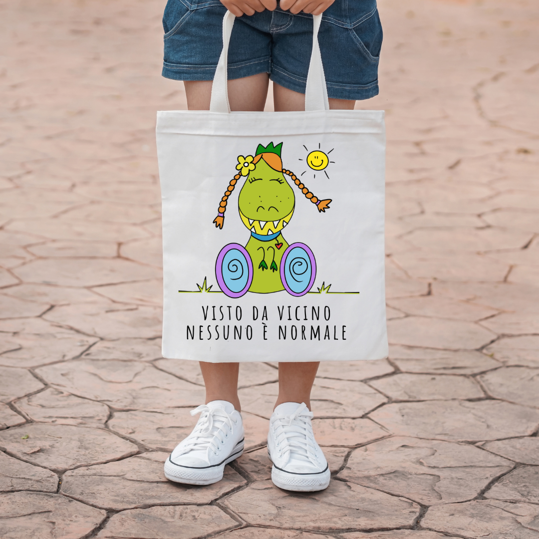 Borsa shopper con l'illustrazione di Dina, il dinosauro con disabilità, che porta un messaggio positivo di inclusione e accettazione.